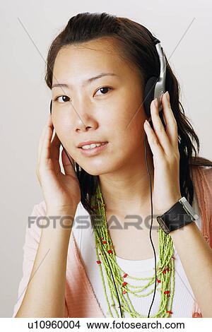 Picture - Portrait of a young woman wearing headphones and listening to music. Fotosearch
