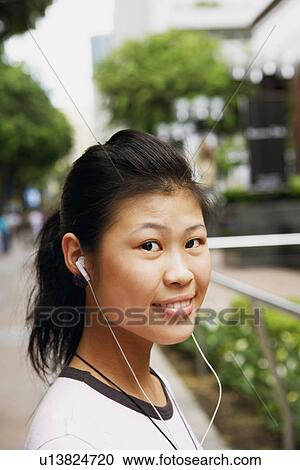 Stock Image - Portrait of a young woman wearing headphones and listening to music. Fotosearch
