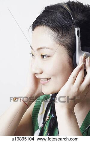 Picture - Side profile of a young woman listening to music. Fotosearch