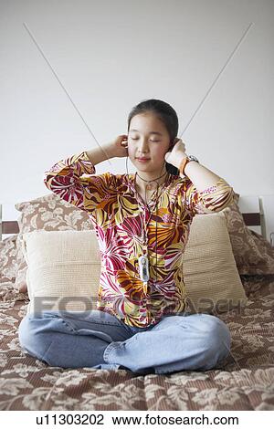Stock Image - Young woman listening to music with her eyes closed. Fotosearch