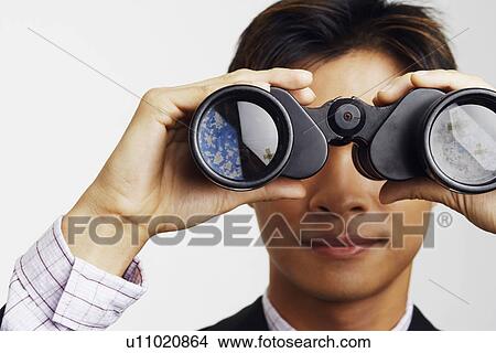 Picture - Close-up of a businessman looking through a pair of binoculars. Fotosearch