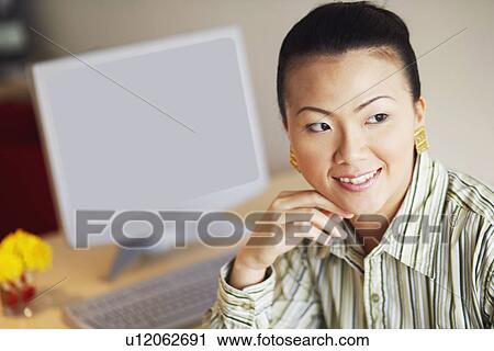 Stock Image - Close-up of a businesswoman looking sideways and smiling. Fotosearch