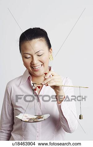 Close-up of a businesswoman weighing paper currency with coins on a weighing scale and smiling View Large Photo Image Picture - Close-up of a businesswoman weighing paper currency with coins on a weighing scale and smiling. Fotosearch
