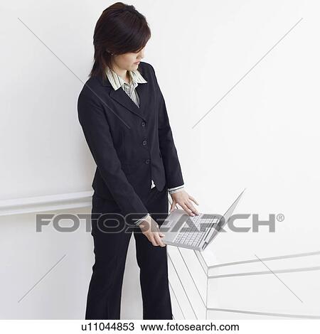 Stock Image - High angle view of a businesswoman using a laptop on the staircase. Fotosearch
