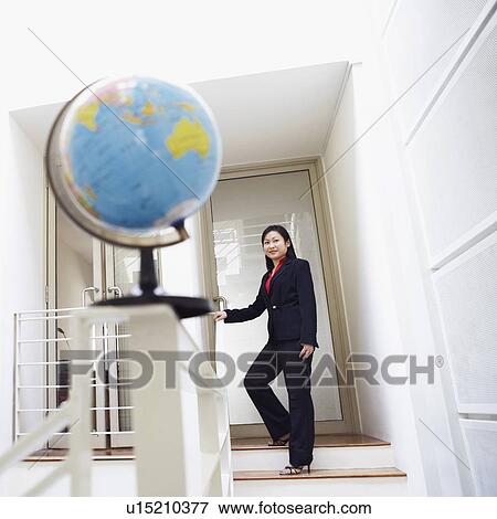 Stock Photo - Low angle view of a businesswoman standing on the staircase and smiling. Fotosearch