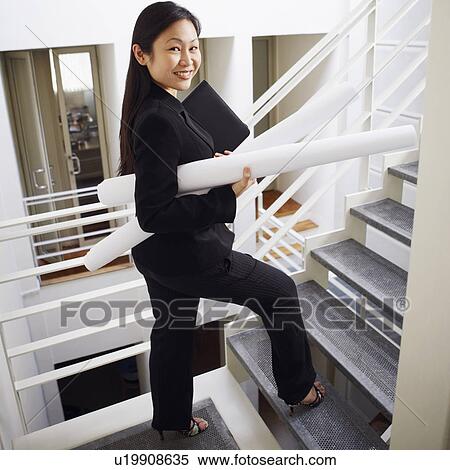 Portrait of a businesswoman carrying rolled up charts and smiling View Large Photo Image Stock Photography - Portrait of a businesswoman carrying rolled up charts and smiling. Fotosearch