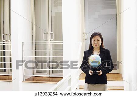 Portrait of a businesswoman holding a globe and smiling View Large Photo Image Picture - Portrait of a businesswoman holding a globe and smiling. Fotosearch
