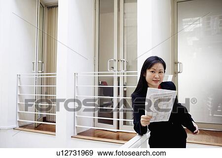 Stock Photo - Portrait of a businesswoman holding a newspaper and smiling. Fotosearch