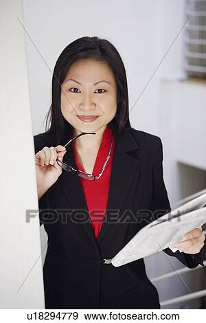 Stock Photo - Portrait of a businesswoman holding a newspaper and smiling. Fotosearch