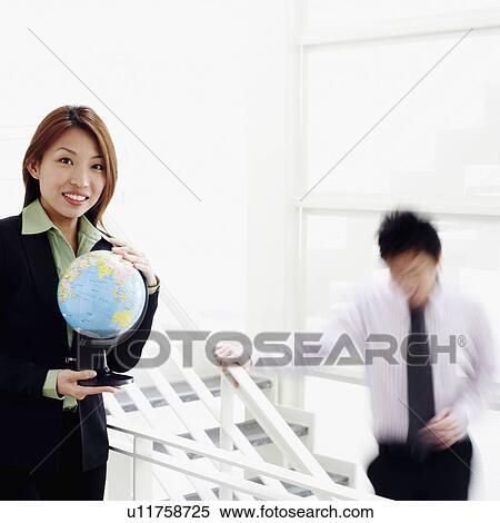Stock Photography - Portrait of a businesswoman holding a globe and smiling. Fotosearch