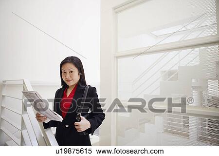 Stock Photography - Portrait of a businesswoman holding a newspaper and smiling. Fotosearch
