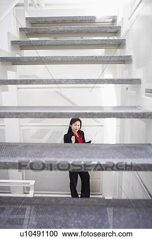Stock Image - Portrait of a businesswoman holding eyeglasses and smiling. Fotosearch
