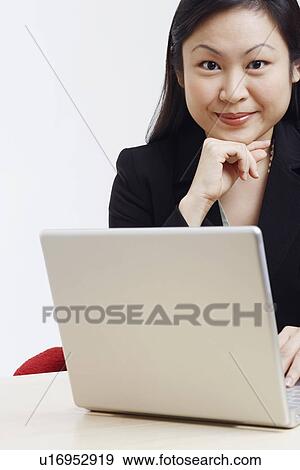 Stock Photo - Portrait of a businesswoman sitting in front of a laptop. Fotosearch