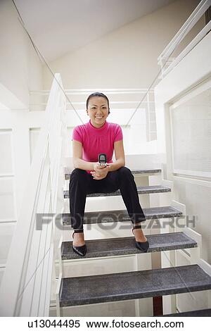 Portrait of a businesswoman sitting on a staircase and holding a mobile phone View Large Photo Image Stock Photography - Portrait of a businesswoman sitting on a staircase and holding a mobile phone. Fotosearch