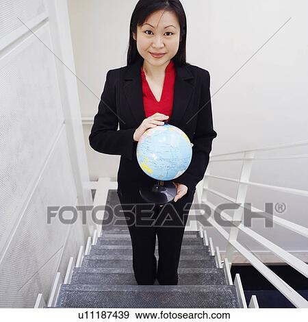 Portrait of a businesswoman standing on a staircase and holding a globe View Large Photo Image Stock Photo - Portrait of a businesswoman standing on a staircase and holding a globe. Fotosearch
