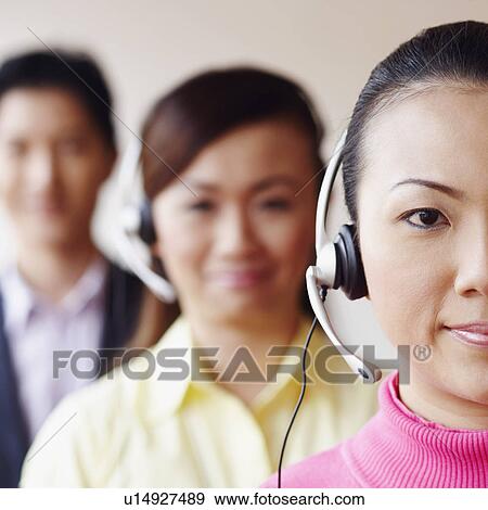 Stock Photo - Portrait of a female customer service representative with two colleagues in the background. Fotosearch