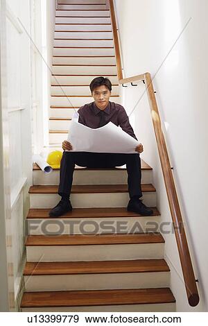 Portrait of a male architect holding blueprints on a staircase View Large Photo Image Stock Photo - Portrait of a male architect holding blueprints on a staircase. Fotosearch