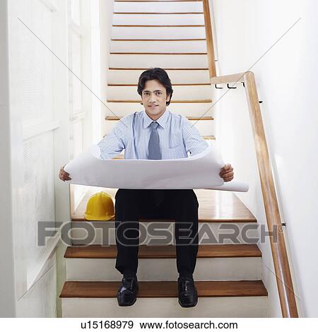 Stock Photo - Portrait of a male architect holding blueprints on a staircase. Fotosearch