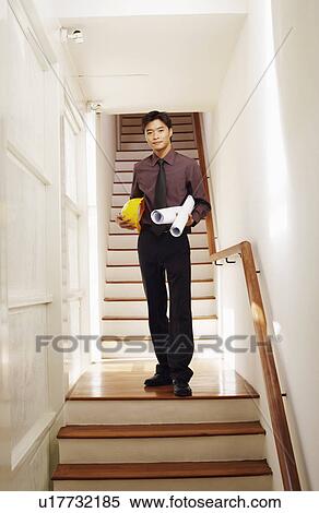 Portrait of a male architect holding rolled up blueprints and a hardhat on a staircase View Large Photo Image Stock Photography - Portrait of a male architect holding rolled up blueprints and a hardhat on a staircase. Fotosearch