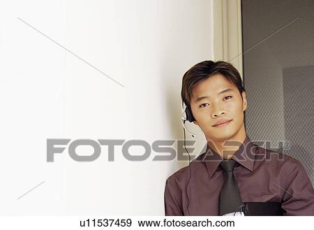 Stock Photo - Portrait of a male customer service representative holding a file and a mobile phone. Fotosearch