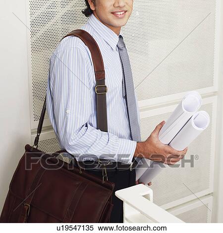 Side profile of a male architect holding rolled up blueprints and smiling View Large Photo Image Stock Photography - Side profile of a male architect holding rolled up blueprints and smiling. Fotosearch