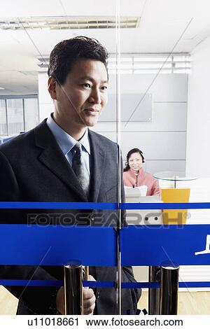 Stock Image - Close-up of a businessman standing in an office with a mature woman wearing a headset. Fotosearch