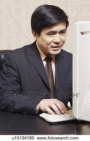 Stock Image - Close-up of a businessman working on a computer in an office. Fotosearch