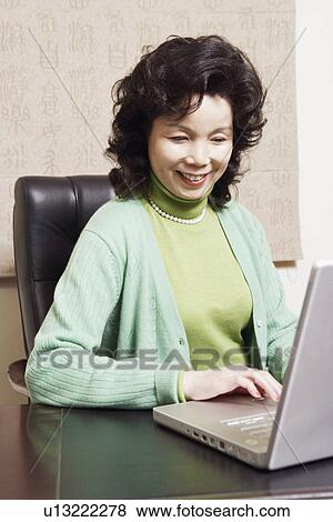 Stock Photo - Close-up of a businesswoman using a laptop smiling. Fotosearch