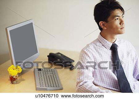 Close-up of a young man sitting in an office and thinking View Large Photo Image Stock Image - Close-up of a young man sitting in an office and thinking. Fotosearch