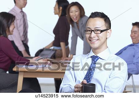 Portrait of a businessman sitting on a chair holding a coffee cup View Large Photo Image Stock Photography - Portrait of a businessman sitting on a chair holding a coffee cup. Fotosearch