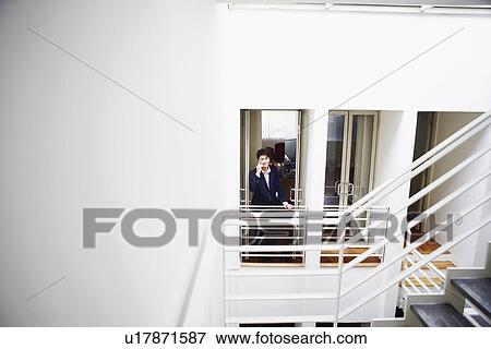 Portrait of a businessman standing at the doorway of an office and talking on a mobile phone View Large Photo Image Stock Photo - Portrait of a businessman standing at the doorway of an office and talking on a mobile phone. Fotosearch