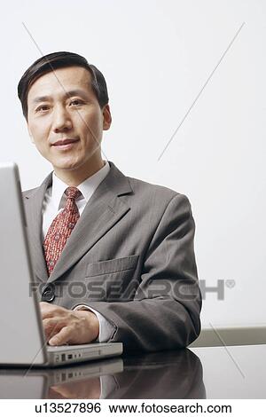 Portrait of a businessman using a laptop View Large Photo Image Stock Photograph - Portrait of a businessman using a laptop. Fotosearch