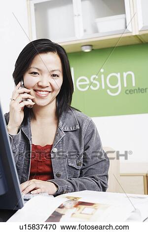 Portrait of a businesswoman sitting in front of a computer using a mobile phone View Large Photo Image Stock Image - Portrait of a businesswoman sitting in front of a computer using a mobile phone. Fotosearch