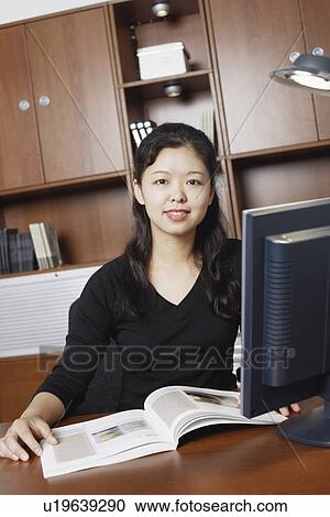 Stock Image - Portrait of a businesswoman sitting with a magazine on the table. Fotosearch