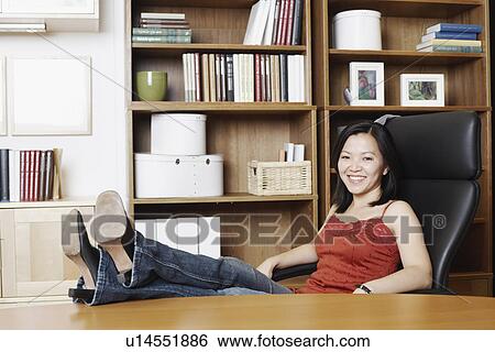 Stock Photograph - Portrait of a businesswoman sitting with her legs on the table. Fotosearch