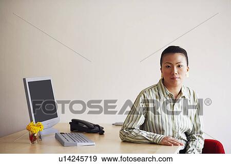 Portrait of a young woman sitting in an office View Large Photo Image Stock Photo - Portrait of a young woman sitting in an office. Fotosearch