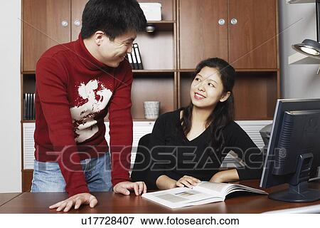 Young man standing with a mid adult woman sitting beside him smiling View Large Photo Image Stock Photo - Young man standing with a mid adult woman sitting beside him smiling. Fotosearch