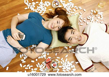 Stock Photo - High angle view of a young couple lying on the floor and smiling. Fotosearch