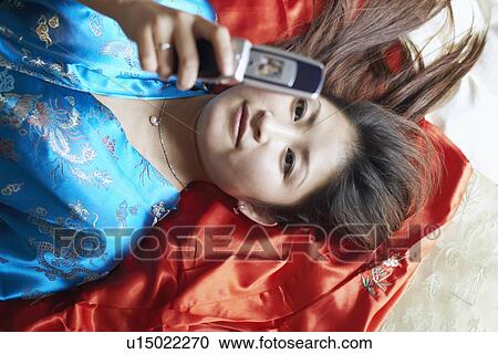Stock Image - High angle view of a young woman holding a mobile phone. Fotosearch