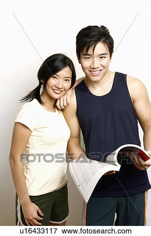 Portrait of a young man holding a directory and standing with a young woman View Large Photo Image Stock Photo - Portrait of a young man holding a directory and standing with a young woman. Fotosearch