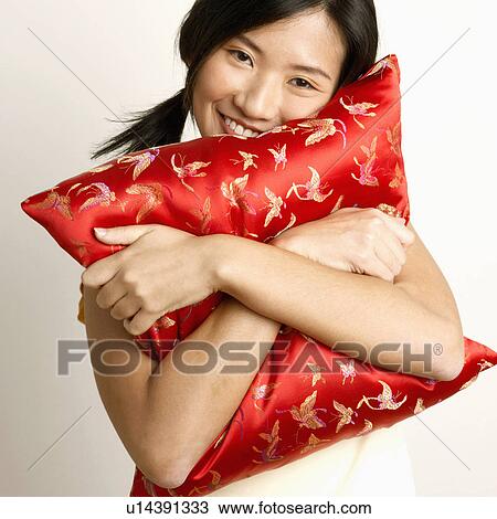Portrait of a young woman hugging a cushion and smiling View Large Photo Image Stock Image - Portrait of a young woman hugging a cushion and smiling. Fotosearch