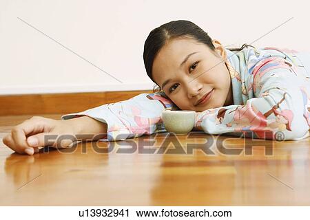Portrait of a young woman lying in front of a tea cup View Large Photo Image Stock Image - Portrait of a young woman lying in front of a tea cup. Fotosearch