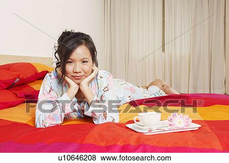 Portrait of a young woman lying on the bed and smiling View Large Photo Image Stock Photo - Portrait of a young woman lying on the bed and smiling. Fotosearch