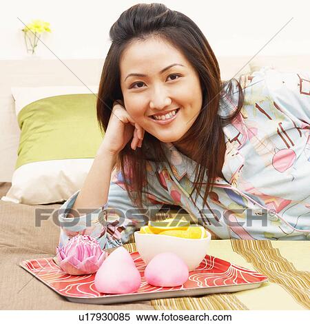 Stock Photography - Portrait of a young woman lying on the bed and smiling. Fotosearch