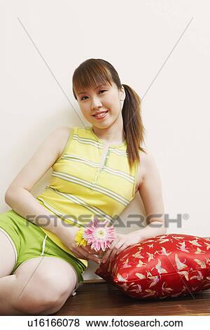 Portrait of a young woman sitting on a bench and holding flowers View Large Photo Image Stock Photo - Portrait of a young woman sitting on a bench and holding flowers. Fotosearch
