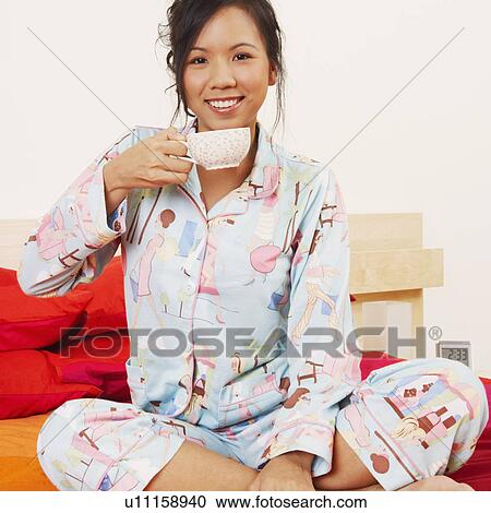 Portrait of a young woman sitting on the bed and smiling View Large Photo Image Stock Image - Portrait of a young woman sitting on the bed and smiling. Fotosearch