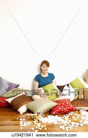 Stock Image - Portrait of a young woman sitting on the floor and smiling. Fotosearch