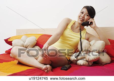 Stock Photography - Portrait of a young woman smiling and talking on the telephone. Fotosearch