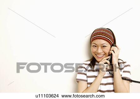 Portrait of a young woman talking on the telephone and smiling View Large Photo Image Picture - Portrait of a young woman talking on the telephone and smiling. Fotosearch