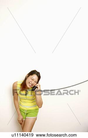 Stock Photo - Portrait of a young woman talking on the telephone and smiling. Fotosearch